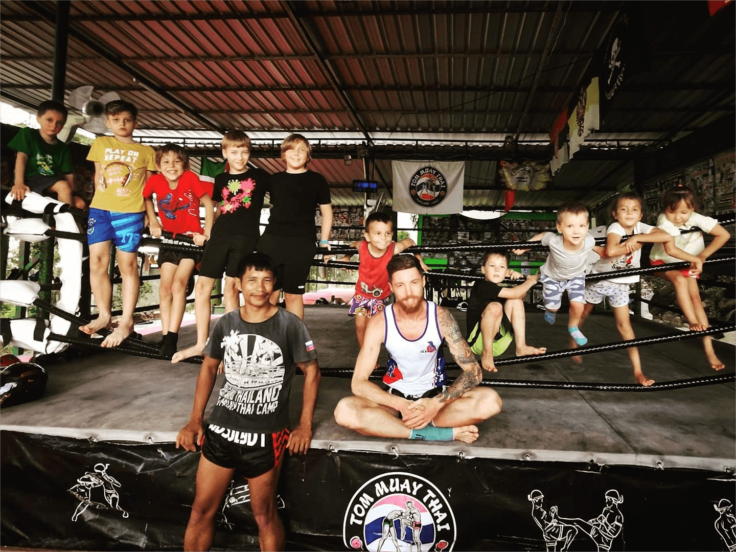 Trainer of the Tom Muay Thai Gym in Koh Samui and children together in the boxing ring.