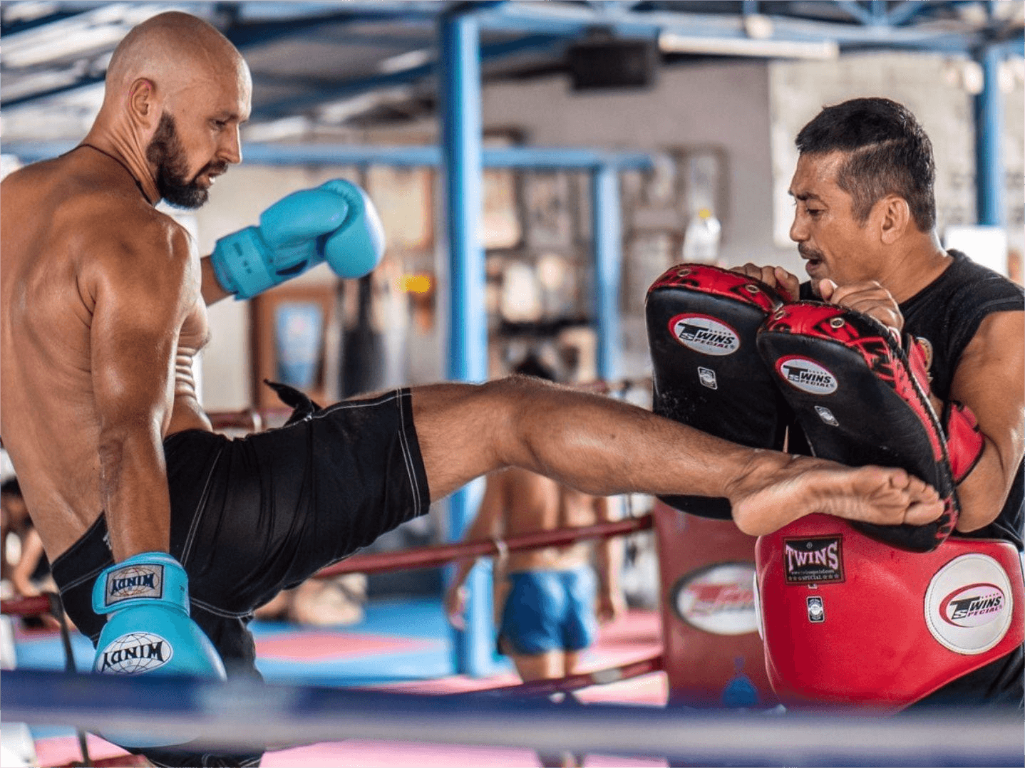 Fighter trains pad work with coach at Chinnarach Muay Thai Gym in Koh Samui